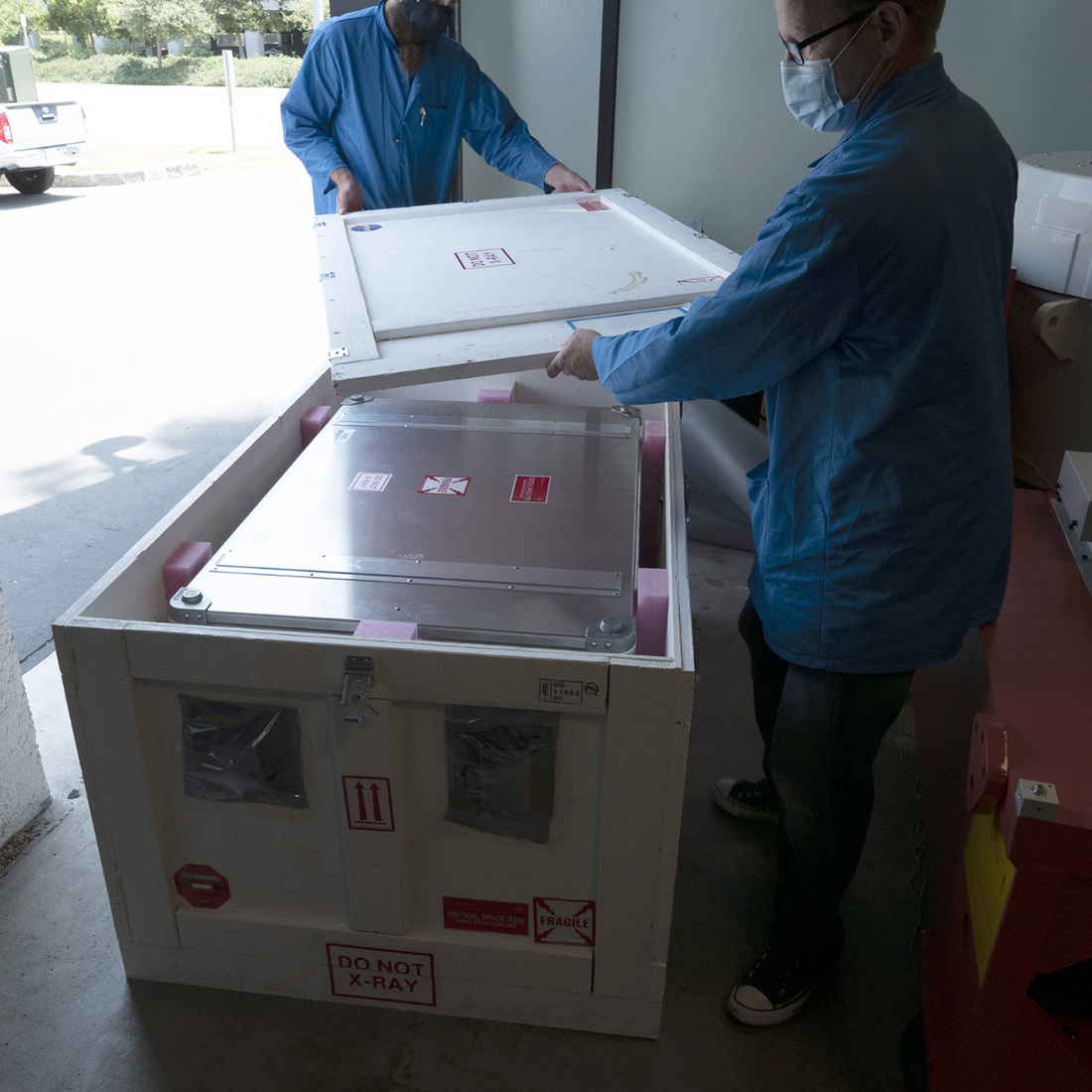 Photo of the ShadowCam container getting placed into a padded, heavy wooden box prior to being loaded into the shipping van.