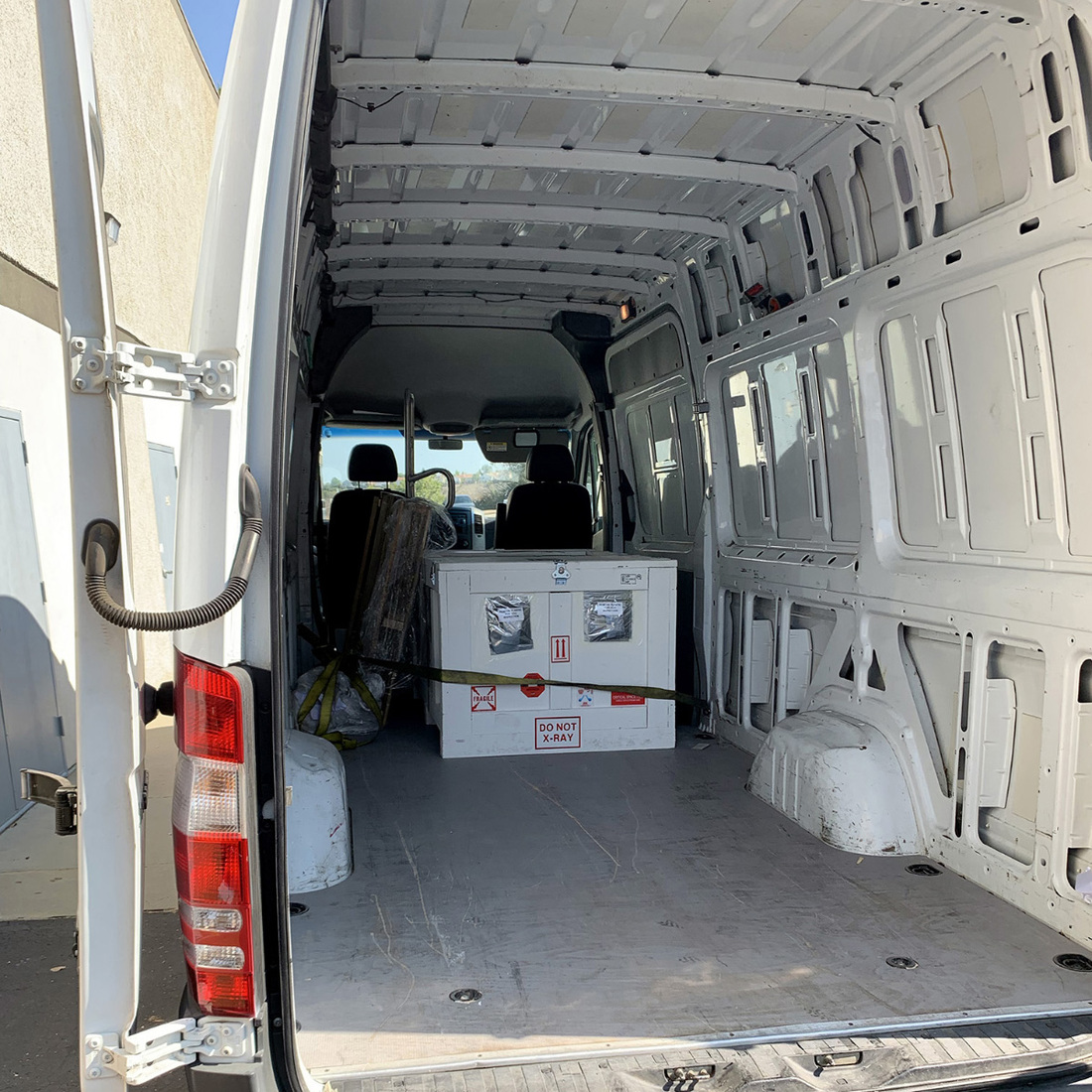 Photo of the ShadowCam shipping container secured with straps inside the courier van.