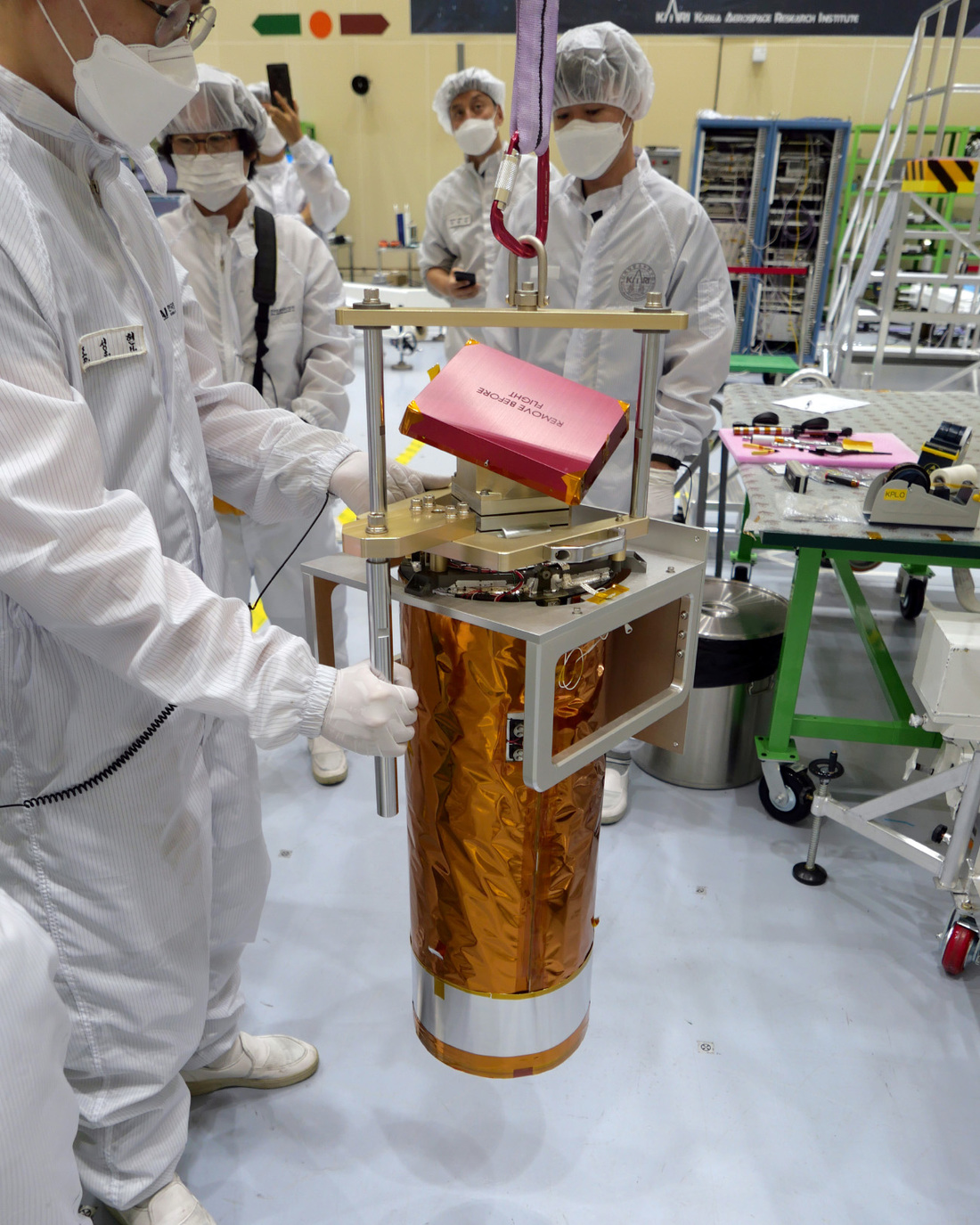 Image of the KARI team stabilizing and inspecting ShadowCam as it's suspended from the hoist.